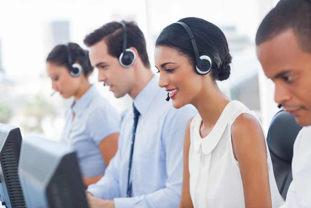 Smiling call center employees sitting in line with their headset